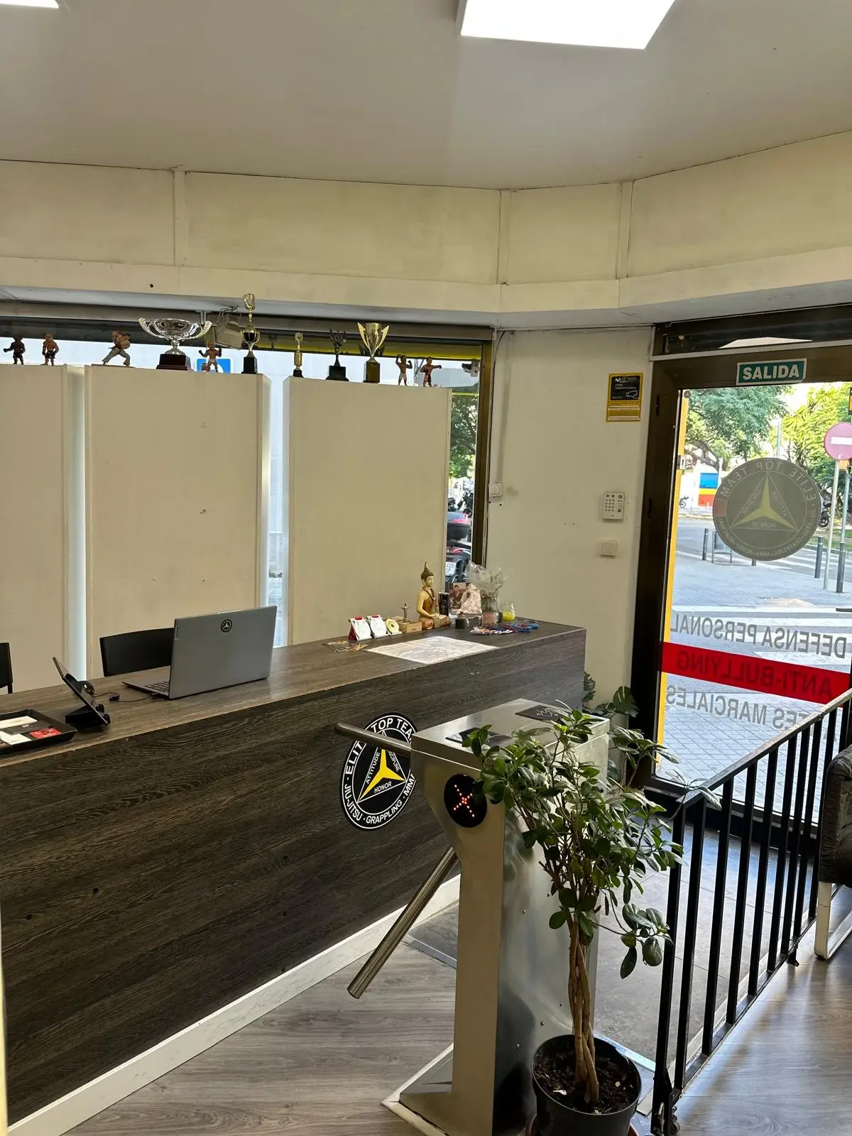 Mostrador de recepción con los trofeos del club y el torno de acceso